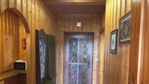 A wooden interior with a door, a fire extinguisher, and a small table.