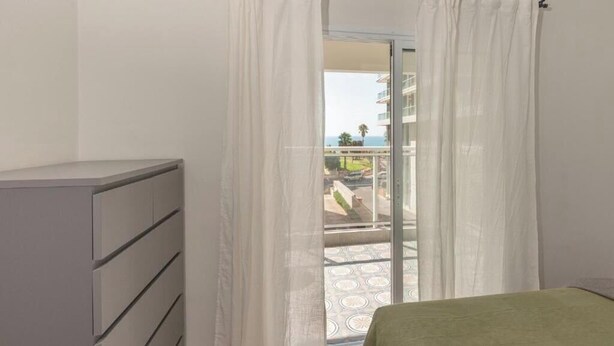 Een slaapkamer met een bed, een grijze garderobe en een balkon met uitzicht.