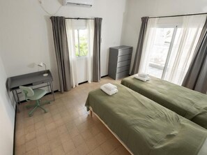 A bedroom with two beds, a desk, a chair, a dresser, and a window with curtains. - Sea view apartment with balcony (Netanya)