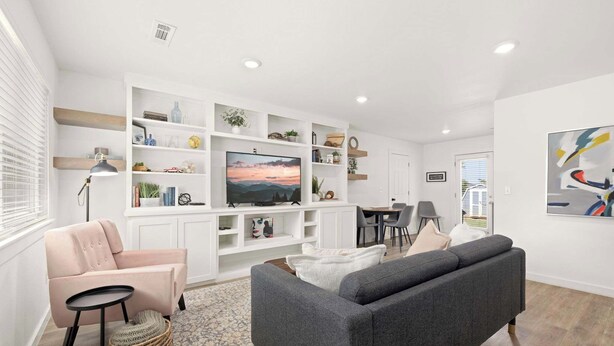 A modern living room with a sofa, armchair, and TV on a white entertainment unit.