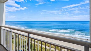 A balcony with a view of a beach and ocean.