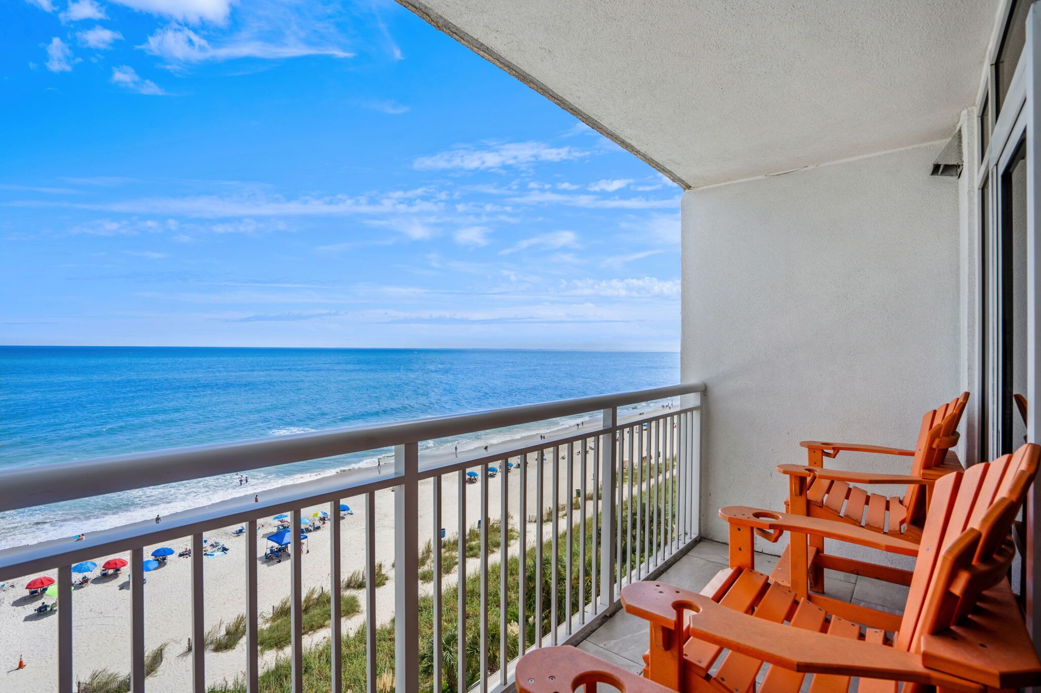 A balcony with a view of the beach and ocean.