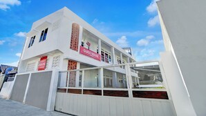 Un bâtiment moderne avec une enseigne indiquant « Maison d’hôtes », de grandes fenêtres et un espace extérieur couvert.