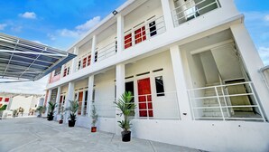 Un immeuble à plusieurs étages doté d’un espace extérieur abrité, de plantes en pot et surplombant un ciel dégagé.