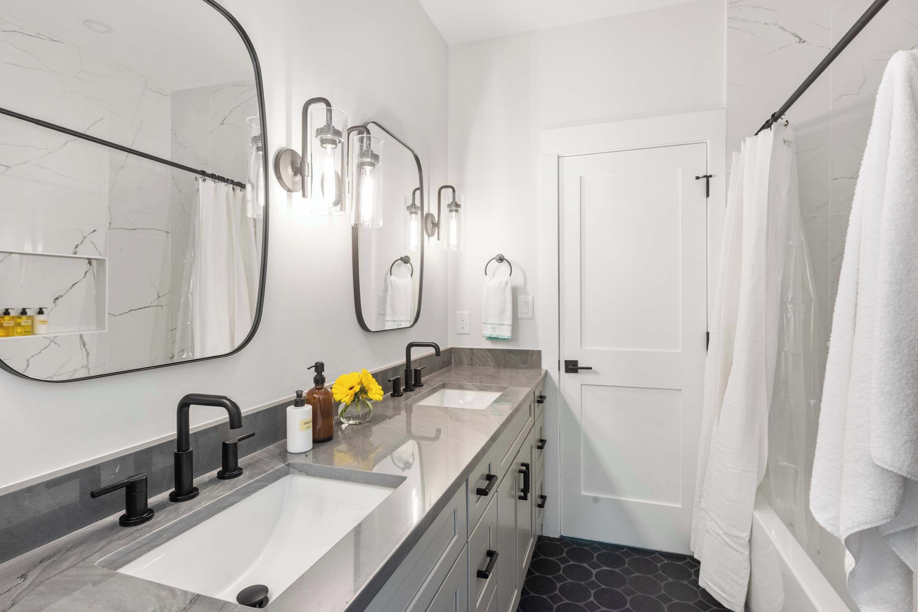 Un baño moderno con lavamanos doble, un espejo grande y zona de ducha.