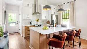 Une cuisine moderne avec des meubles blancs, un îlot central et des luminaires suspendus.