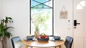Un tavolo da pranzo con sedie, una ciotola di frutta e una finestra vista alberi.