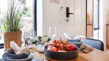 A dining table with a fruit bowl, a woven basket, and a vase with flowers.