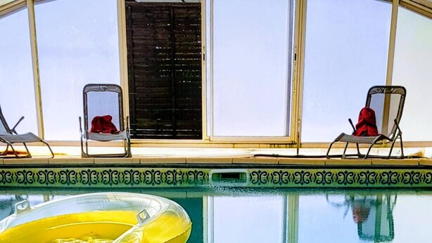 A pool with two lounge chairs and a yellow float. - Cottage with covered pool in Auvergne (Le Theil)