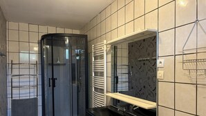 A bathroom with a glass shower enclosure, a black sink, and a mirror with a towel rack. - Cottage with covered pool in Auvergne (Le Theil)