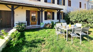 A two-story building with a covered patio and a garden area. - Charming and Comfortable Cottage in Saint-Haon-le-Châtel, Pets Allowed (Saint-Haon-le-Châtel)