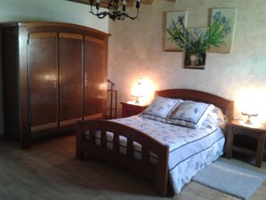 Une chambre à coucher avec un lit en bois, deux tables de chevet, une commode, une armoire et un lustre.