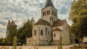 A historic church with a prominent tower, surrounded by trees and a well-maintained garden.