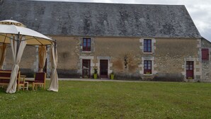 Un bâtiment rustique doté d’un toit en pente, de murs en pierre et de nombreuses fenêtres équipées de volets.