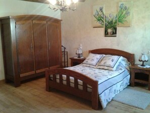A bedroom with a wooden bed, a nightstand, a wardrobe, and a chandelier. - Charming renovated guest room with parking in La Berthenoux (La Berthenoux)