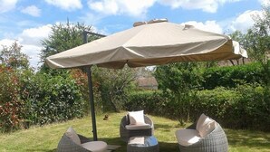 A patio area with a large umbrella, wicker chairs, and a round table.