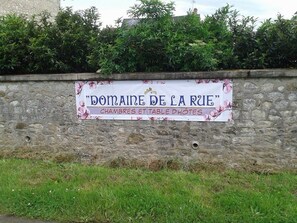 A stone wall with a sign that reads "Domaine de la Rue" and mentions "chambres et table dhotes". - Charming renovated guest room with parking in La Berthenoux (La Berthenoux)