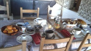 A round dining table with chairs, set with various dishes, cups, and a pitcher.