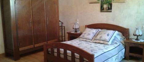 A bedroom with a wooden bed, a nightstand, a wardrobe, and a chandelier.