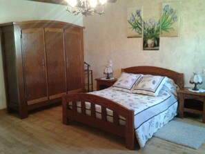 Een slaapkamer met een houten bed, een nachtkastje, een kledingkast en een kroonluchter.