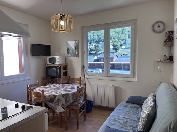 Una cocina compacta con una mesa de comedor, microondas y televisor.