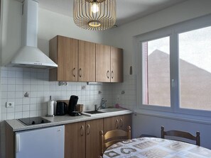 Una cocina con armarios de madera, un refrigerador blanco, un lavamanos y una ventana con vistas.