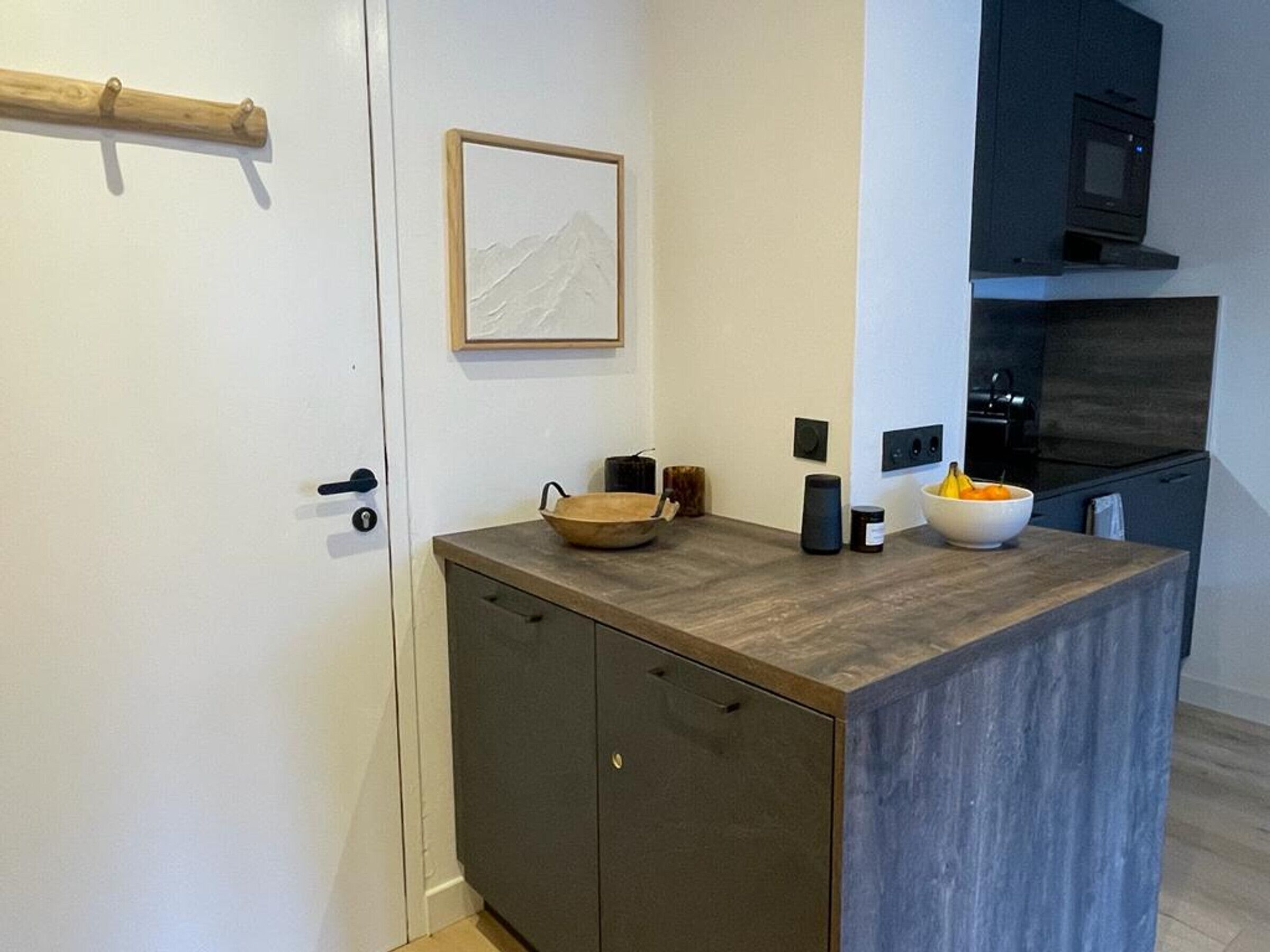 Une cuisine compacte dotée d’un plan de travail en bois, d’un four encastré et d’un four à micro-ondes.