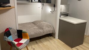 A compact room with a bed, a small desk, a chair, a television, and a projector. - Studio cabin for 4 people, 3* with NW facing balcony (Valloire)