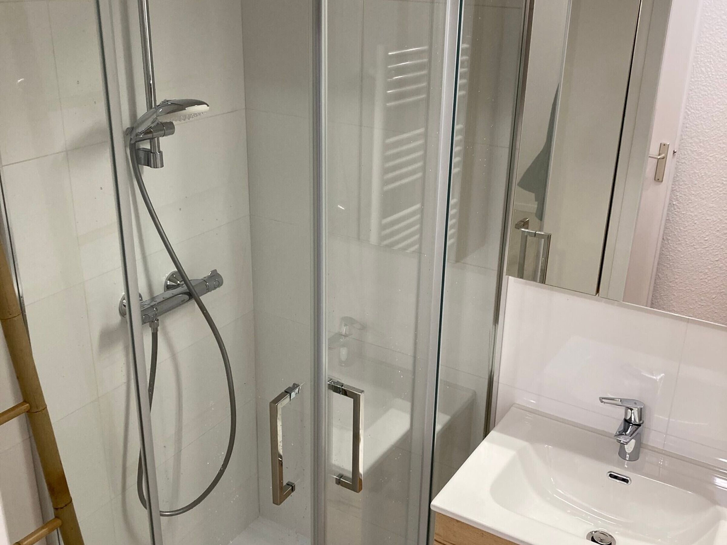 Een douche met glazen wanden, een handdouche en een handmengkraan.