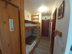 A narrow hallway with bunk beds, a wooden door, a thermostat, and a door with a heart-shaped decoration. - Cozy studio for 4 people in Valfréjus with balcony (Valfréjus)