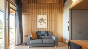 A modern living room with a grey sofa, a wooden slatted wall, and a framed artwork.