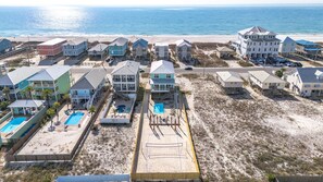 Un hotel frente a la playa con varias construcciones, piscina y zona de acceso a la playa.