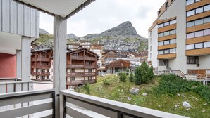 Een balkon met uitzicht op traditionele houten gebouwen en een berg op de achtergrond.