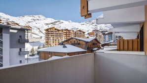 A balcony with a view of snow-covered mountains and wooden buildings.
