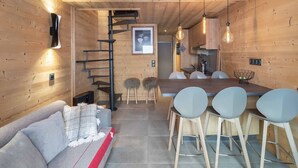 Een modern interieur met een houten vloer, een bank, een eettafel met stoelen, een keukenhoek en een trap.