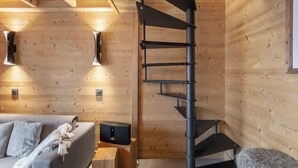 Een modern interieur met een wenteltrap, houten wanden, een bank en een klein tafeltje met een speaker.