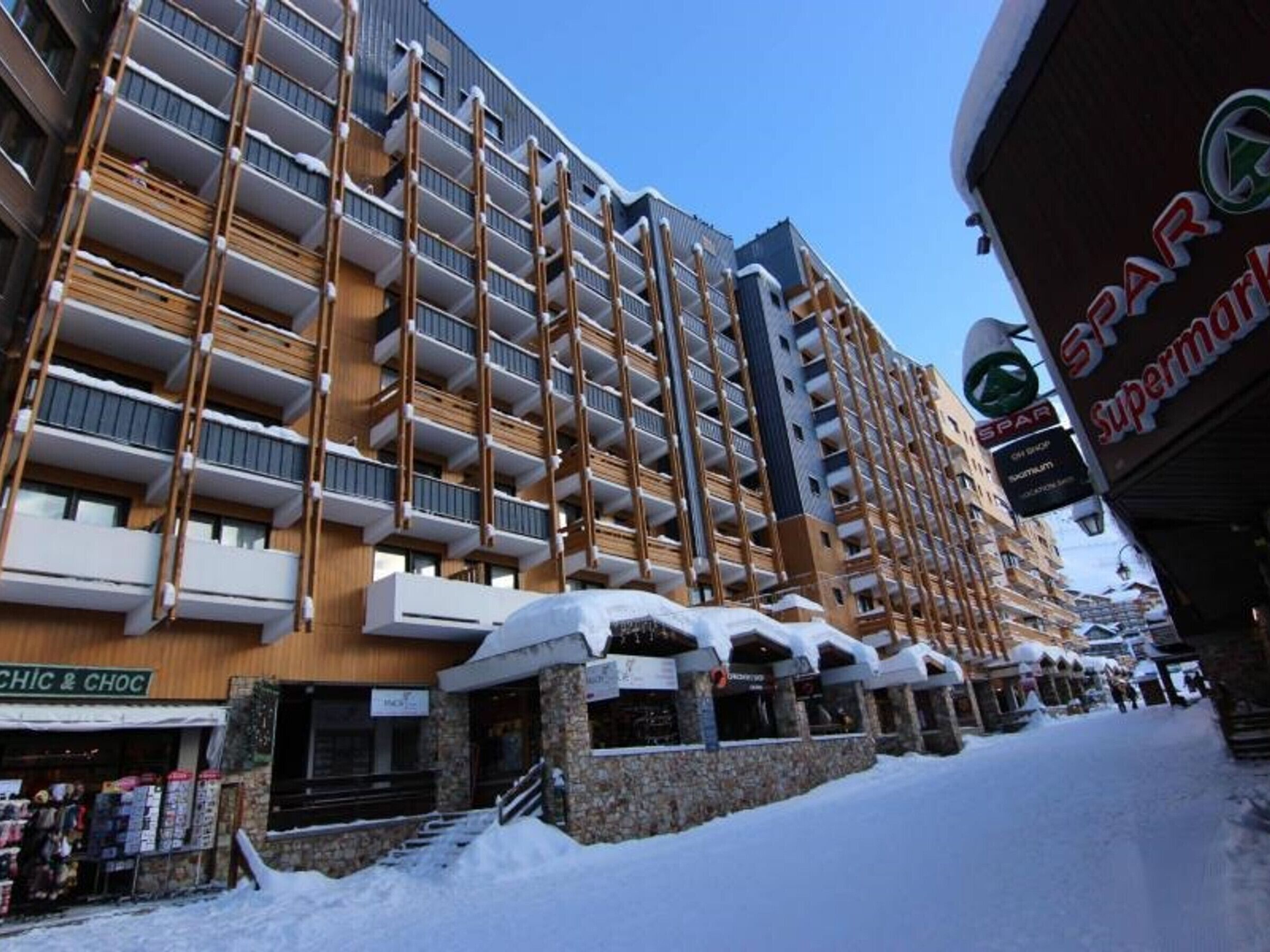 A multi-story hotel with balconies, a storefront named "CHIC & CHOC," and a sign for "SPAR Supermarkt."