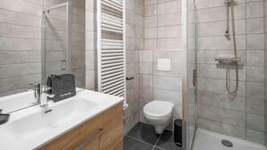A modern bathroom with a shower, toilet, and vanity.