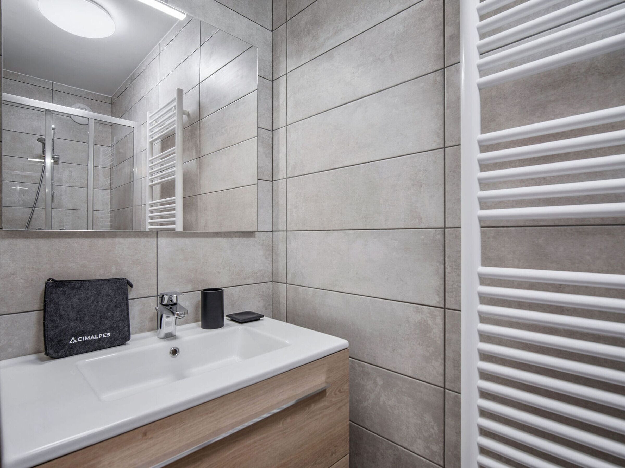 Un baño moderno con lavamanos, espejo y toallero blancos.