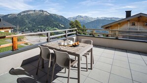 Ein Balkon mit Tisch für Zwei, mit Blick auf eine Berglandschaft.