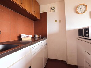 A compact kitchen with a dishwasher, a microwave, and a clock on the wall. - Courchevel 1850 Center, 2-Room Apt, 4 People, Wifi, Balcony (Courchevel)