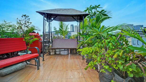 Una terrazza sul tetto con una panca rossa, una zona salotto coperta e piante in vaso.