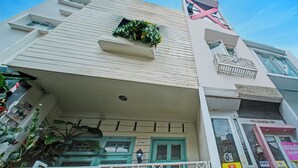 Un edificio a più piani con facciata piatta, un piccolo balcone con ringhiera e una finestra con una pianta.