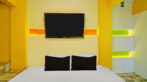 Camera d'albergo con un letto grande, una TV a schermo piatto fissata al muro e illuminazione LED lungo i bordi delle pareti.