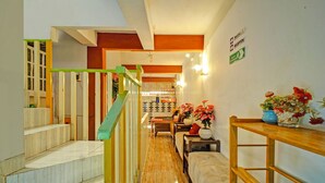 Un corridoio con una scala, una reception e un'area salotto con fiori.