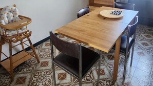 A dining area with a wooden table, chairs, a high chair, and a bookshelf. - 70m2 apartment in Dijon, 4th floor without elevator, 5 minutes from Zenith (Dijon)