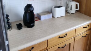 A kitchen with wooden cabinets, a countertop, a toaster, a coffee maker, and a kettle. - 70m2 apartment in Dijon, 4th floor without elevator, 5 minutes from Zenith (Dijon)
