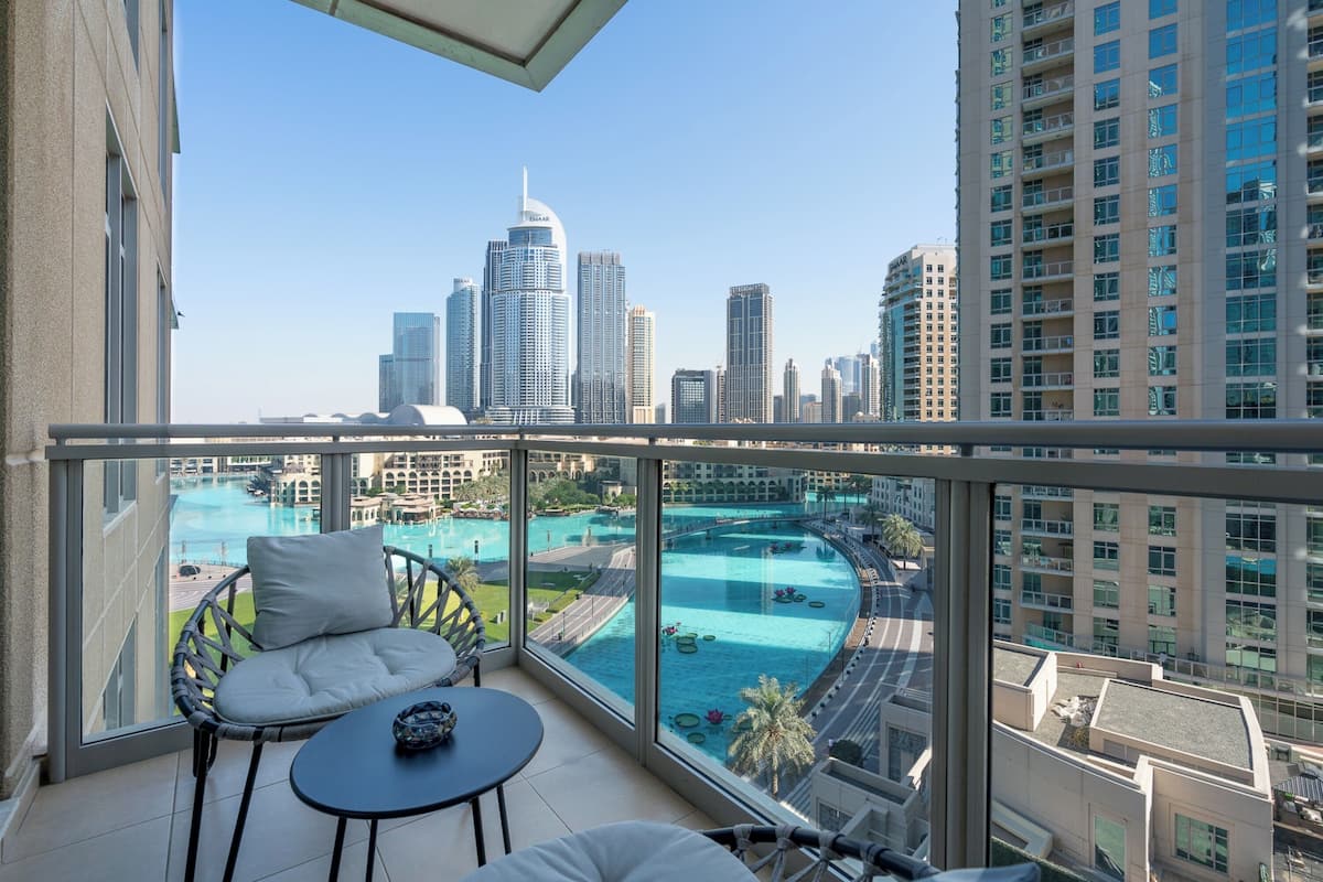 A balcony with a view of a city skyline and a swimming pool.