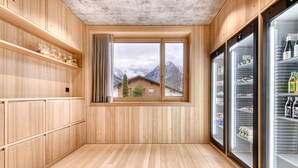 A wooden interior with a large window, wooden shelves, and two refrigerators.