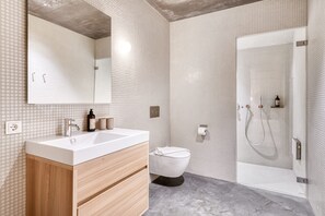 A modern bathroom with a white sink, wooden cabinet, and a glass shower enclosure.
